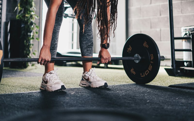 Person learning to lift barbell at Oshawa wellness centre fitness facility