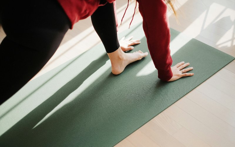 Person performing pilates exercise on green mat in Oshawa wellness centre